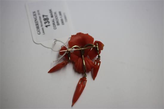 A 19th century gold and coral brooch modelled as three carved satyr masks with three urn shaped drops, 2.5in.